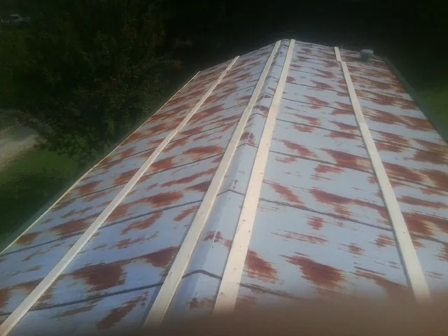 Rusted metal roof panels with new wood purlins before replacement — Storm Damage Roof Repair in Smiths Creek by Roofing Brothers