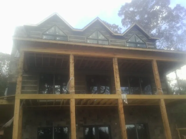 Dormers and porch framing on a large log home under construction — Roof Coating work by our crew in Smiths Creek