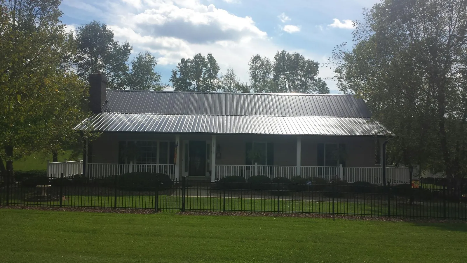 Gray metal roof on a brick ranch with a full width front porch — Gutter Guard Installation work by our crew in Smiths Creek
